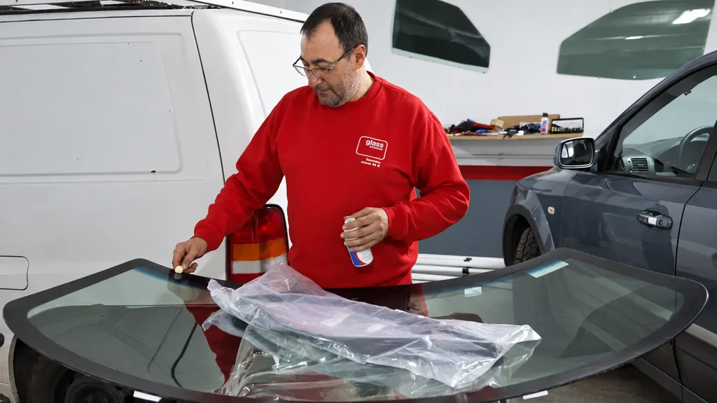 Empleado de A Mariña Glass trabajando sobre un parabrisas dentro del taller